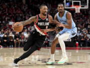 Portland Trail Blazers guard Damian Lillard, left, drives to the basket on Memphis Grizzlies guard De'Anthony Melton, right, during the first half of an NBA basketball game in Portland, Ore., Wednesday, Oct. 27, 2021.