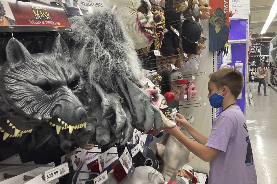 A young customer looks at a Halloween mask at a Party City store, Wednesday, Oct. 6, 2021, in Miami.  Americans continued to spend at a solid clip in September despite rising prices and snarled global supply chains that are limiting the flow of goods. Retail sales rose a seasonally adjusted 0.7%  in September  from the month before, the U.S. Commerce Department said Friday, Oct. 15.
