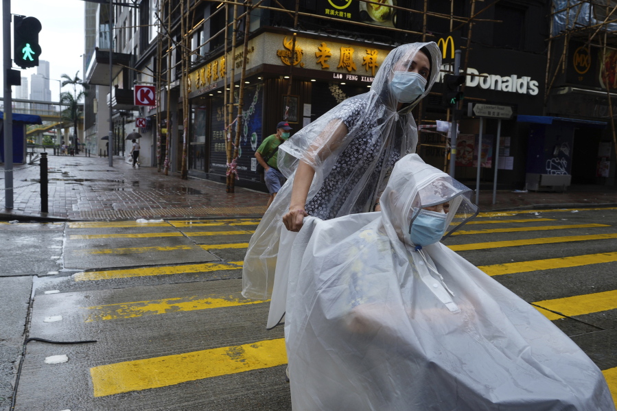 People make their way on an empty street as Typhoon Kompasu passes in Hong Kong Wednesday, Oct. 13, 2021. Hong Kong suspended classes, stock market trading and government services as the typhoon passed south of the city Wednesday.