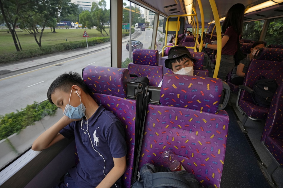 A passenger, front, sleeps on the upper deck of a double-decker bus in Hong Kong, Saturday, Oct. 16, 2021. Travel-starved, sleep-deprived residents might find a new Hong Kong bus tour to be a snooze. The 47-mile, five-hour ride on a double-decker bus around the territory is meant to appeal to people who are easily lulled asleep by long rides.