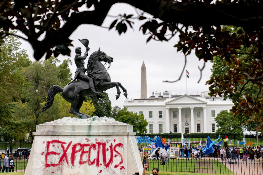 The words "Expect Us" are spray painted on the base of the Andrew Jackson statue in Lafayette Park as Indigenous and environmental activists protest in front of the White House in Washington, Monday, Oct. 11, 2021. The words are part of the phrase "Respect Us, or Expect Us" which indigenous women have been using while protesting oil company Enbridge's Line 3 pipeline through Minnesota. President Joe Biden on Friday issued the first-ever presidential proclamation of Indigenous Peoples Day, lending the most significant boost yet to efforts to refocus the federal holiday celebrating Christopher Columbus toward an appreciation of Native peoples.