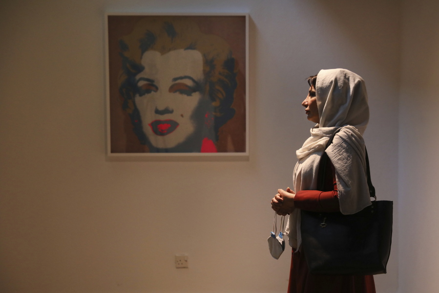 Fatemeh Rezaei, a retired teacher, stands next to Marilyn Monroe portrait by American artist Andy Warhol at Tehran Museum of Contemporary Art in Tehran, Iran on Oct. 19, 2021. Iranians are flocking to Tehran's contemporary art museum to marvel at American pop artist Andy Warhol's iconic work.
