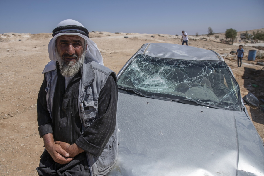A Palestinian man leans on his smashed vehicle following a settlers attack from nearby settlement outposts on his Bedouin community, in the West Bank village of al-Mufagara, near Hebron, Thursday, Sept. 30, 2021. An Israeli settler attack last week damaged much of the village's fragile infrastructure.
