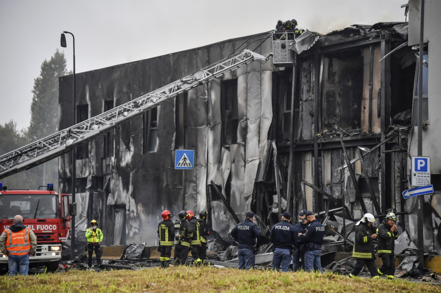 Firefighters work on the site of a plane crash, in San Donato Milanese suburb of Milan, Italy, Sunday, Oct. 3, 2021. According to media reports, a small plane carrying five passengers and the pilot crashed into an apparently vacant office building in a Milan suburb. Their fates were not immediately known.