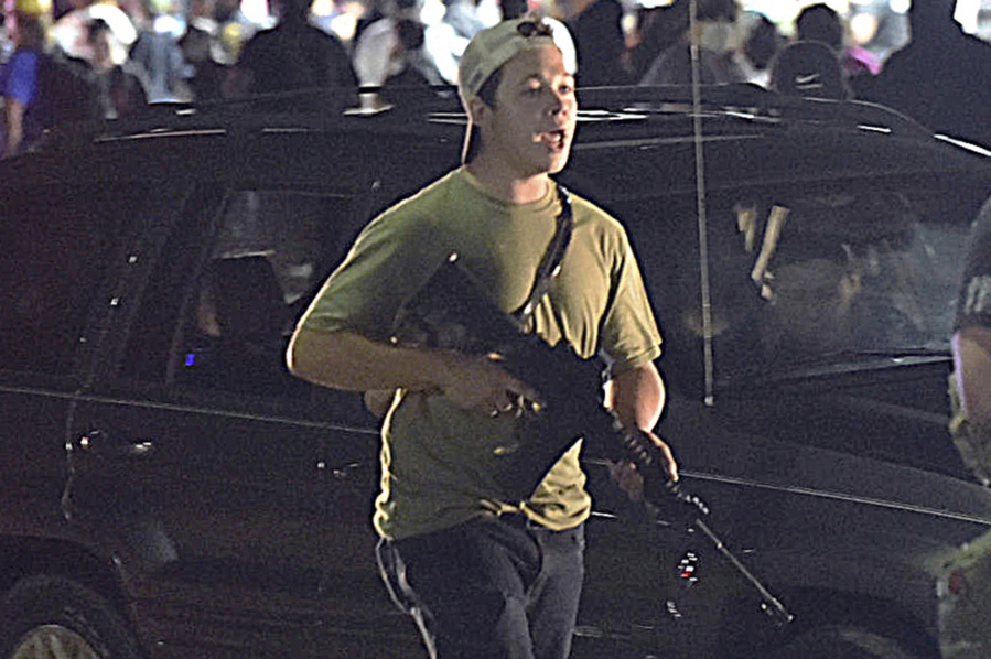 FILE - In this Aug. 25, 2020, file photo, Kyle Rittenhouse carries a weapon as he walks along Sheridan Road in Kenosha, Wis., during a night of unrest following the weekend police shooting of Jacob Blake.  Rittenhouse is white. So were the three men he shot during street protests in Kenosha in 2020. But for many people, Rittenhouse's trial will be watched closely as the latest referendum on race and the American judicial system.