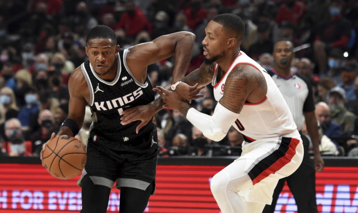 Sacramento Kings guard De'Aaron Fox, left, tries to get past Portland Trail Blazers guard Damian Lillard during the first half of an NBA basketball game in Portland, Ore., Wednesday, Oct. 20, 2021.