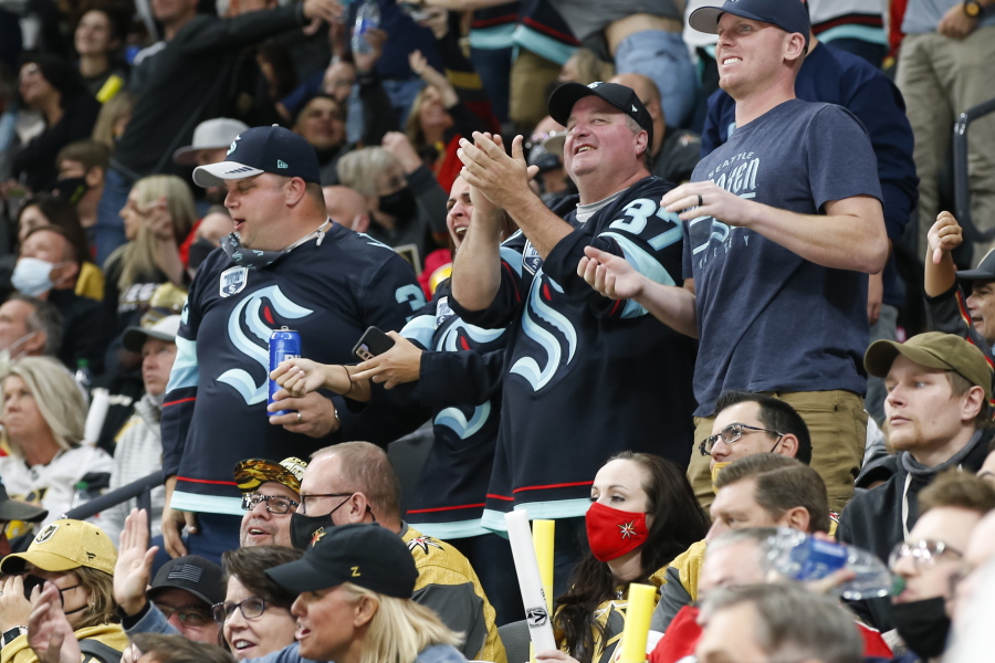 Seattle Kraken fans celebrate the team's goal against the Vegas Golden Knights during the second period of an NHL hockey game Tuesday, Oct. 12, 2021, in Las Vegas.
