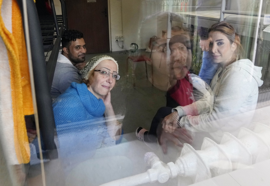 Boshra al-Moallem, bottom left, looks out of the window as she sits in a room with her two sisters and brother-in-law at a refugee center in Bialystok, Poland, on Wednesday, Sept. 29, 2021. After enduring a decade of war in Syria, Boshra al-Moallem and her two sisters seized their chance to flee, but the journey proved terrifying and nearly deadly. Al-Moallem, originally from Homs but who displaced to Damascus by the war, is one of thousands of people who have traveled to Belarus in recent weeks and then found herself helped to cross the border with the help of Belarusian guards, something the EU considers a form of "hybrid war" waged against the bloc with the use of human lives.