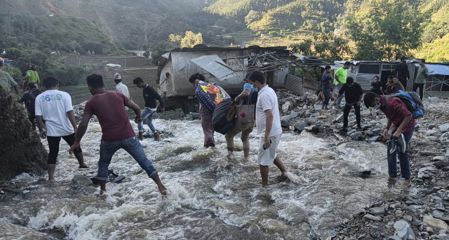 People wade past a flooded area in Dipayal Silgadhi, Nepal, Thursday, Oct. 21, 2021. Floods and landslides triggered by days of torrential rains have killed at least 99 people in Nepal since Monday, officials said.