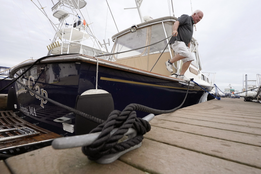 Brad White, of Marshfield, Mass., secures lines for his 33-foot vessel White Cap, at Mill Wharf Marina, Tuesday, Oct. 26, 2021, in Scituate, Mass. Authorities say a powerful autumn storm is bearing down on southern New England, packing potentially damaging winds and threatening to dump as much as six inches of rain in some areas from Tuesday afternoon into Wednesday, Oct. 27. White, a licensed captain, who has been sailing out of Scituate for over 50 years, operates a service called New England Burials At Sea LLC, that provides ash scattering and full body burials at sea.