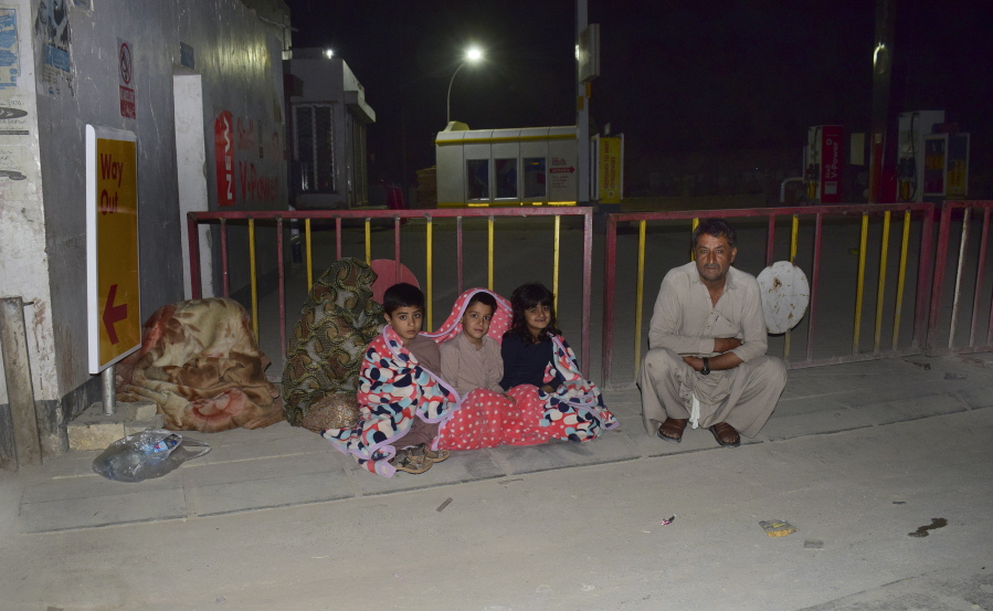 A family gather outside their house following a severe earthquake hit the area, in Quetta, Pakistan, Thursday, Pakistan.