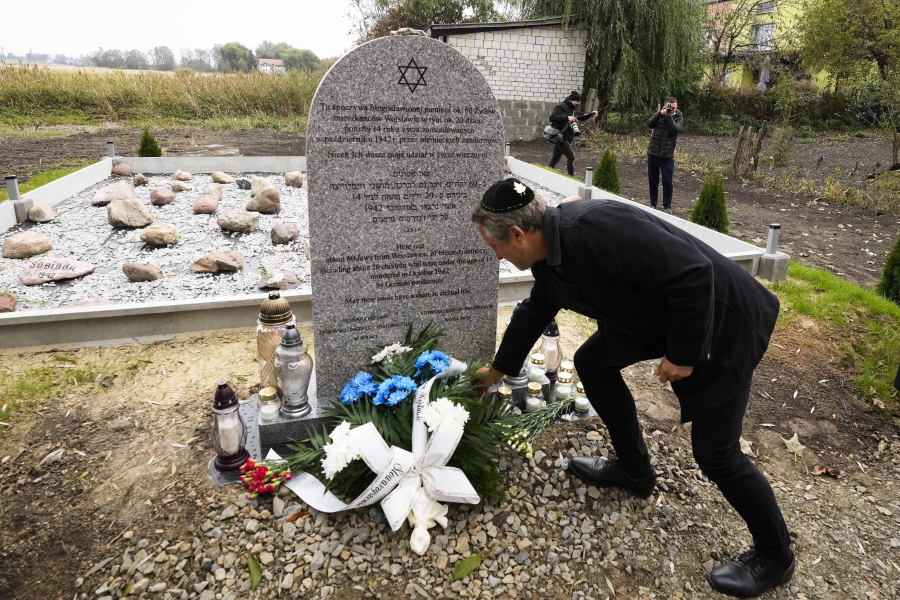 A man lays a candle at a new memorial at a mass grave to some 60 Jews, executed during the Holocaust in Wojslawice, Poland, on Thursday Oct. 14, 2021. It is one of many mass grave sites to be discovered in recent years in Poland, which during World War II was occupied by Adolf Hitler's forces.