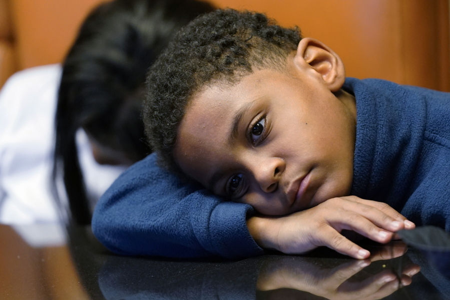 In this Sept. 23, 2021, photo Jhaimarion, 10, reacts as he listens to his mother, Krystal Archie talking with an Associated Press reporter in Chicago. Archie's three children were present when police, on two occasions, just 11 weeks apart, kicked open her front door and tore through their home searching for drug suspects. She'd never heard of the people they were hunting. Her oldest child, Savannah was 14 at the time; her youngest, Jhaimarion, was seven. They were ordered to get down on the floor.  (AP Photo/Nam Y.
