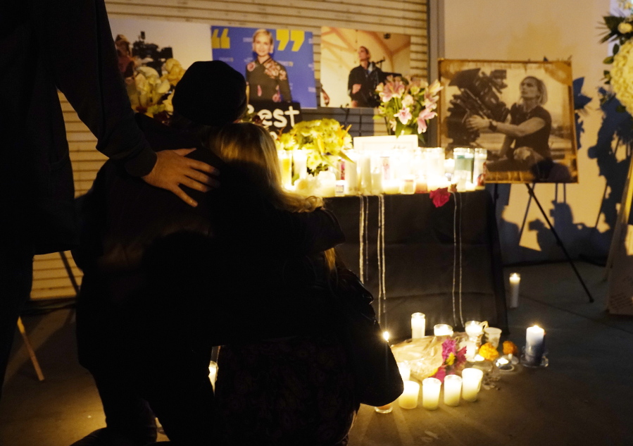 Attendees embrace at a candlelight vigil for the late cinematographer Halyna Hutchins, pictured in photographs in the background, Sunday, Oct. 24, 2021, in Burbank, Calif. A prop firearm discharged last Thursday by actor Alec Baldwin, while producing and starring in a Western movie in Santa Fe, N.M., killed Hutchins and wounded director Joel Souza.