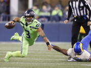 Seattle Seahawks quarterback Russell Wilson goes down as he tries to get a pass off against the Los Angeles Rams during the second half of an NFL football game, Thursday, Oct. 7, 2021, in Seattle.