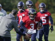 Seattle Seahawks quarterback Russell Wilson (3) keeps his injured hand in a pad as he runs through a warmup drill with backup quarterback Geno Smith (7) behind him during NFL football practice, Wednesday, Oct. 13, 2021, in Renton, Wash. Wilson had surgery on his hand last Friday, and Smith is expected to be the starting quarterback Sunday when the Seahawks play the Pittsburgh Steelers on the road. (AP Photo/Ted S.