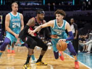 Charlotte Hornets guard LaMelo Ball (2) drives around Portland Trail Blazers forward Robert Covington (33) after Hornets center Mason Plumlee (24) set a screen during the first half of an NBA basketball game, Sunday, Oct. 31, 2021, in Charlotte, N.C.