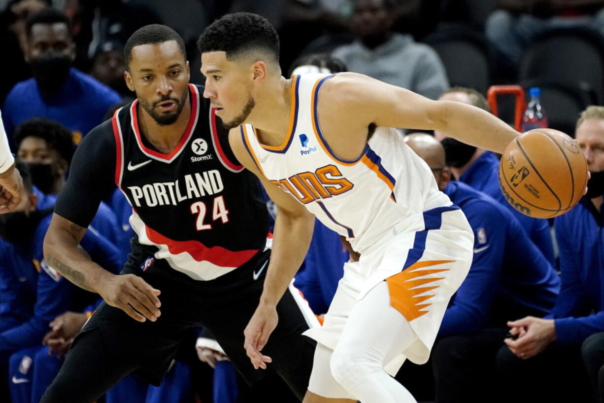 Phoenix Suns guard Devin Booker (1) looks to pass as Portland Portland Trail Blazers forward Norman Powell (24) defends during the first half of a preseason NBA basketball game, Wednesday, Oct. 13, 2021, in Phoenix.