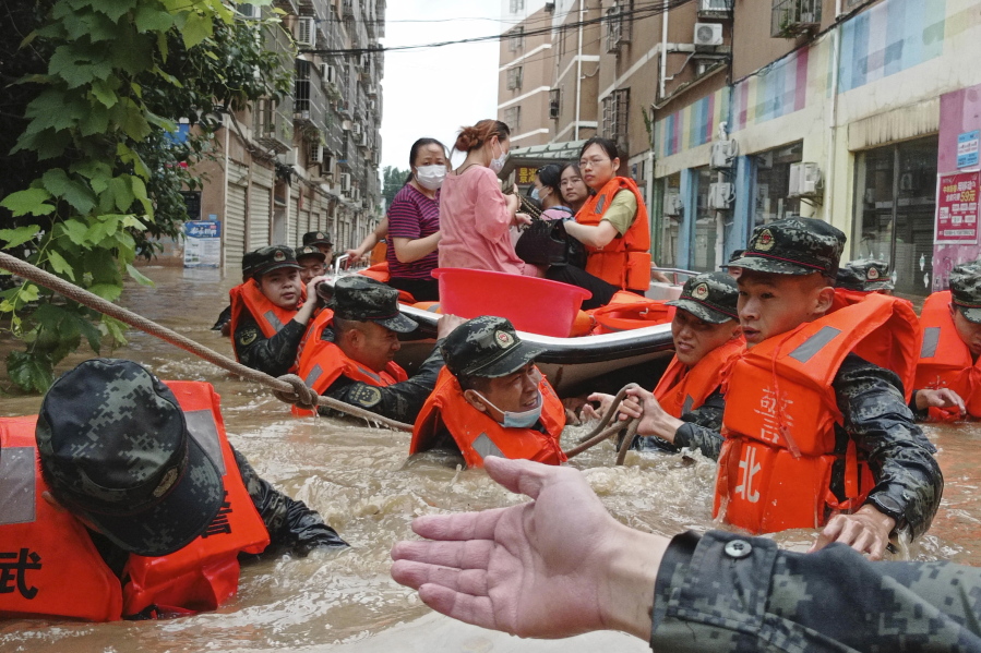 FILE - In this Thursday, Aug. 12, 2021 file photo, paramilitary police work to evacuate people trapped in a flooded area in Suizhou in central China's Hubei Province. Flooding in central China continued to cause havoc in both cities and rural areas. According to a United Nations report released on Tuesday, Oct. 5, 2021, much of the world is unprepared for the floods, hurricanes and droughts expected to worsen with climate change and urgently needs better warning systems to avert water-related disasters.