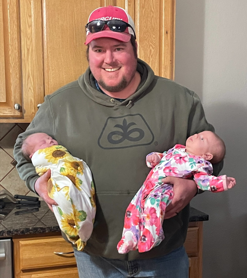 In this image provided by courtesy of Janet Baker, Danny Baker holds his daughter Haylen and niece Maggie, they were born one month apart, on March 3, 2021, in Milford, Kan. The 28-year-old seed hauler from Riley, Kansas, contracted COVID-19 over the summer, spent more than a month in the hospital and died Sept. 14.