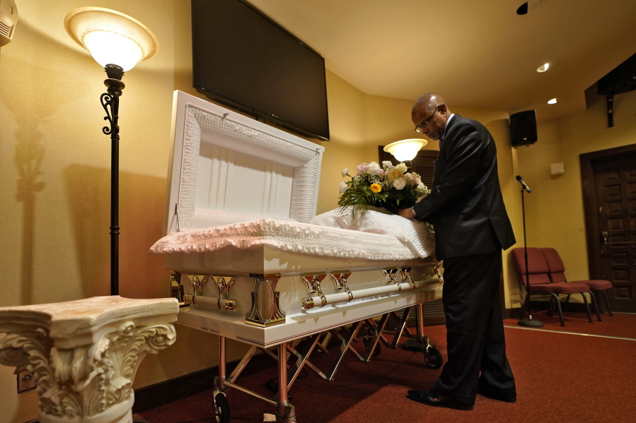 FILE - In this Thursday, Sept. 2, 2021 file photo, a funeral director arranges flowers on a casket before a service in Tampa, Fla. According to a study published Thursday, Oct. 7, 2021, by the medical journal Pediatrics, the number of U.S. children orphaned during the COVID-19 pandemic may be larger than previously estimated, and the toll has been far greater among Black and Hispanic Americans.