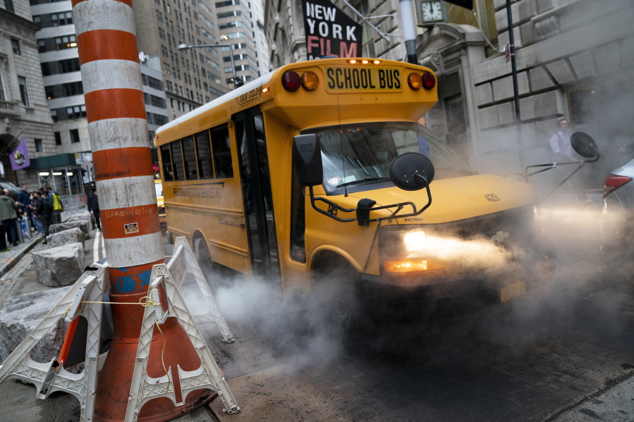 A school bus passes through a steam vent on a morning route, Monday, Oct. 4, 2021, in the Manhattan borough of New York.