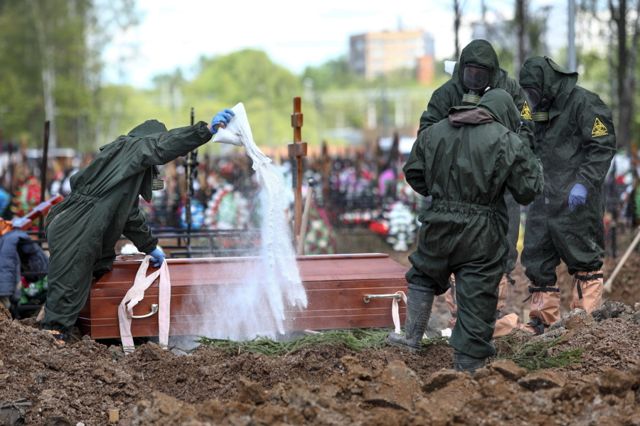 FILE - In this May 15, 2020, file photo, cemetery workers in protective suits disinfect a grave as they bury a COVID-19 victim in a section of the Butovskoye cemetery reserved for coronavirus victims outside Moscow, Russia. Coronavirus deaths in Russia hit a record on Friday, Oct. 1, 2021 for the fourth straight day, and confirmed cases continued to surge as well. Russia's state coronavirus task force reported 887 deaths, the country's highest daily number in the pandemic. The previous record, from a day earlier, stood at 867.