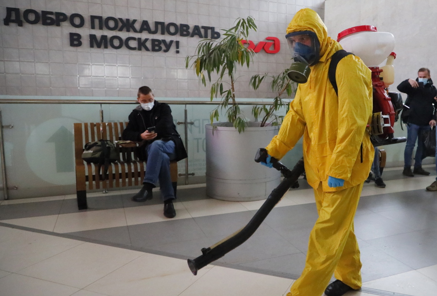An employee of the Federal State Center for Special Risk Rescue Operations of Russia Emergency Situations disinfects Leningradsky railway station in Moscow, Russia, Tuesday, Oct. 19, 2021, with the sign reading "Welcome to Moscow" on the wall. Russia registered another daily record of coronavirus deaths Tuesday as rapidly surging contagion raised pressure on the country's health care system. The daily coronavirus mortality numbers have been surging for weeks and topped 1,000 for the first time over the weekend amid sluggish vaccination rates and the government's reluctance to toughen restrictions.
