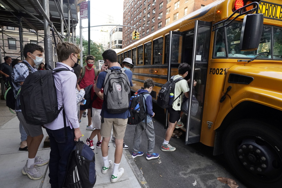 FILE -- In this Sept. 13, 2021, file photo, students board a school bus on New York's Upper West Side. Even as most students return to learning in the classroom this school year, disruptions to in-person learning, from missing one day because of a late school bus to an entire two weeks at home due to quarantine, remain inevitable as families and educators navigate the ongoing pandemic.