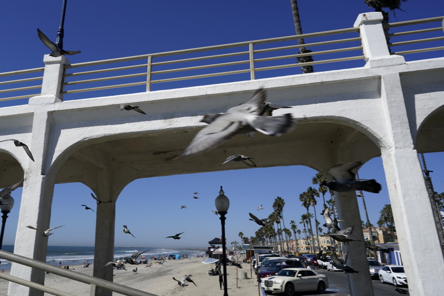 Birds fly past a bridge connecting the Oceanside pier to Pacific Street Friday, Oct. 15, 2021, in Oceanside, Calif. The iconic bridge is deteriorating because the city lacks the money for a roughly $25 million rehabilitation. One reason the project has slowed while projects in other cities are moving ahead revolves around the American Rescue Plan -- the sweeping COVID-19 relief law championed by President Joe Biden and congressional Democrats that is pumping billions of dollars to states and local governments.