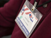 Ballot inspection board member Dennis Olson wears a sticker on his badge in honor of the current election while working at the Clark County Elections Office on Tuesday morning.