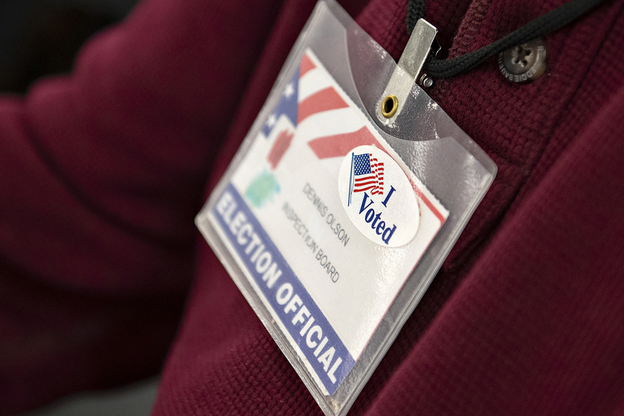 Ballot inspection board member Dennis Olson wears a sticker on his badge in honor of the current election while working at the Clark County Elections Office on Tuesday morning.