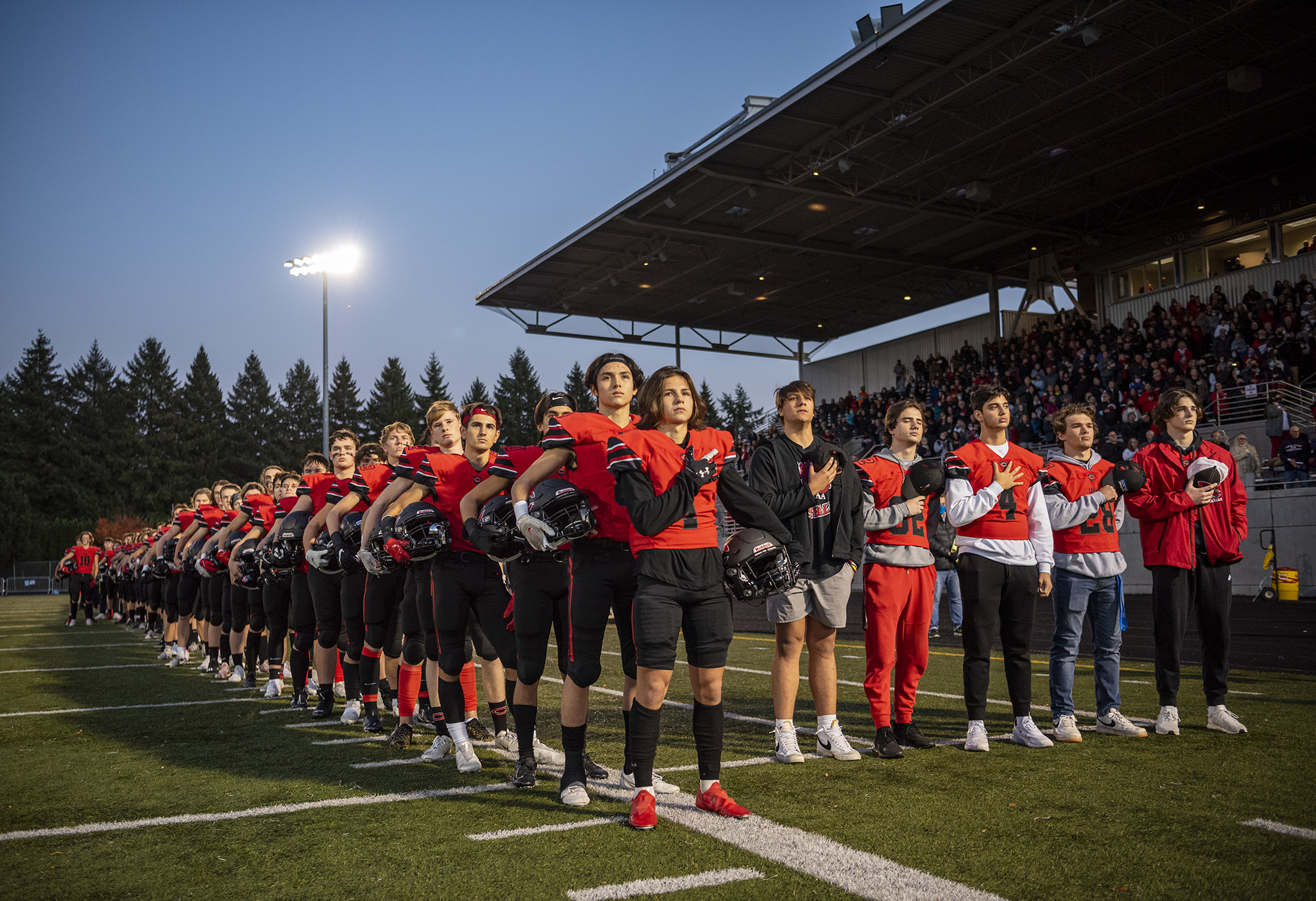 Camas High School football players stand during the national anthem Friday, Nov. 5, 2021, before the Papermakers’ playoff game against Mount Rainier at Doc Harris Stadium.