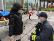Fourth-grader Maria Bella, left, tries on warm winter coats with the help of Capt. Marc Patchin at Marshall Elementary School on Friday morning. The Vancouver Firefighters Union (I.A.F.F. Local 452) in cooperation with the City of Vancouver Fire Department, private donors and local businesses donated coats to local children.
