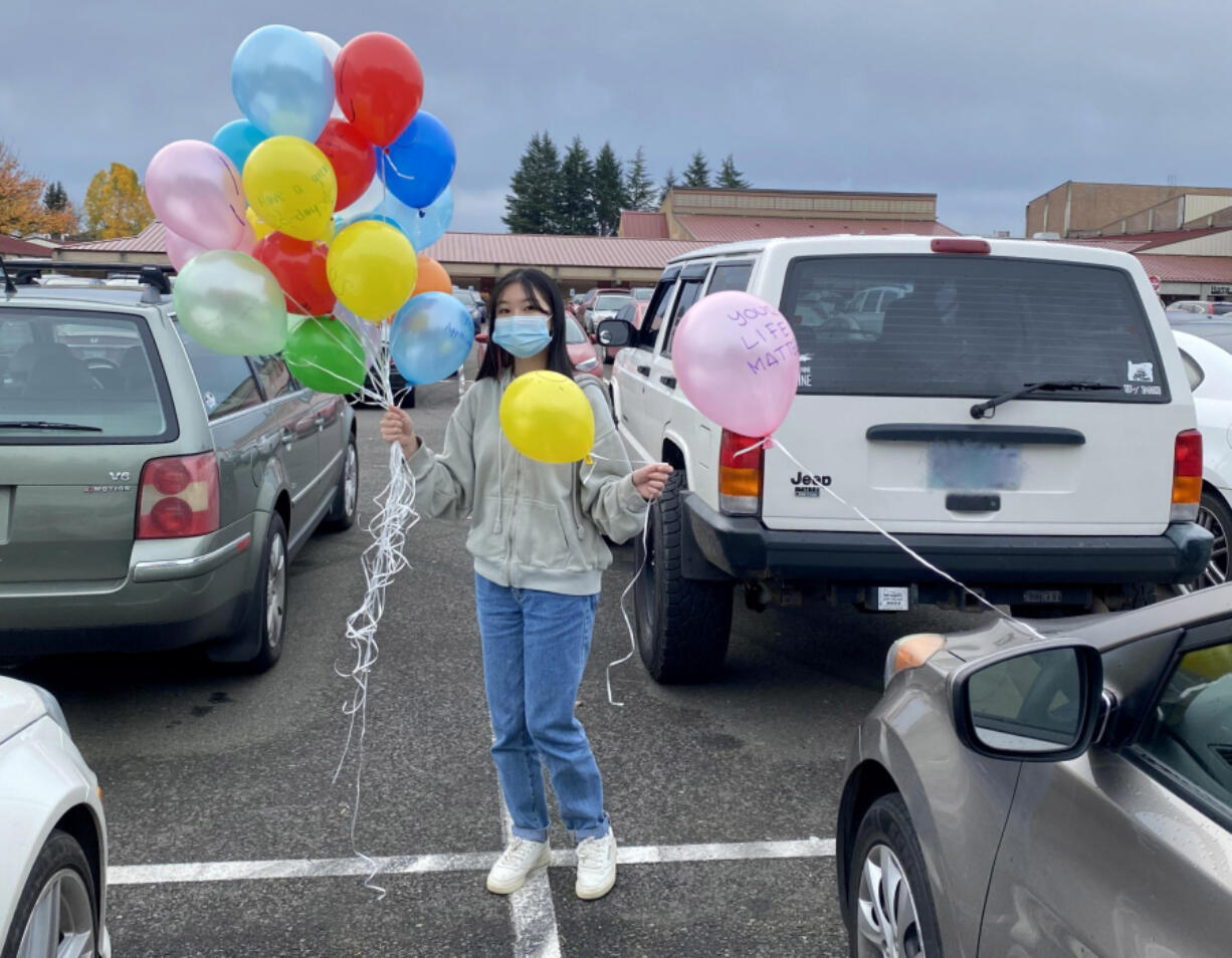Prairie High School freshman Leena Dang attaches balloons with inspirational messages to cars in the parking lot.