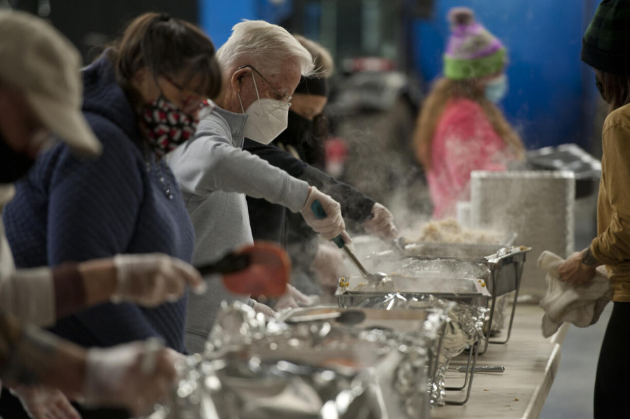 Volunteer Vern Toedtli of Vancouver, at center, stirs the bean and corn station at the turkey dinner assembly line Thursday at the Clark County Event Center at the Fairgrounds. About 1,600 turkey dinners were prepared and delivered by Clark County volunteers to the needy this Thanksgiving.