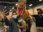 Julio Riscajche and his son Julian, 3, take a selfie on Saturday with Jojo the Deinonychus, with minder Brendon Grimes of Jurassic Quest at right. Families and dinosaur fans of all ages converged on the Clark County Event Center at the Fairgrounds to see a variety of life-size animatronic dinosaurs this weekend.