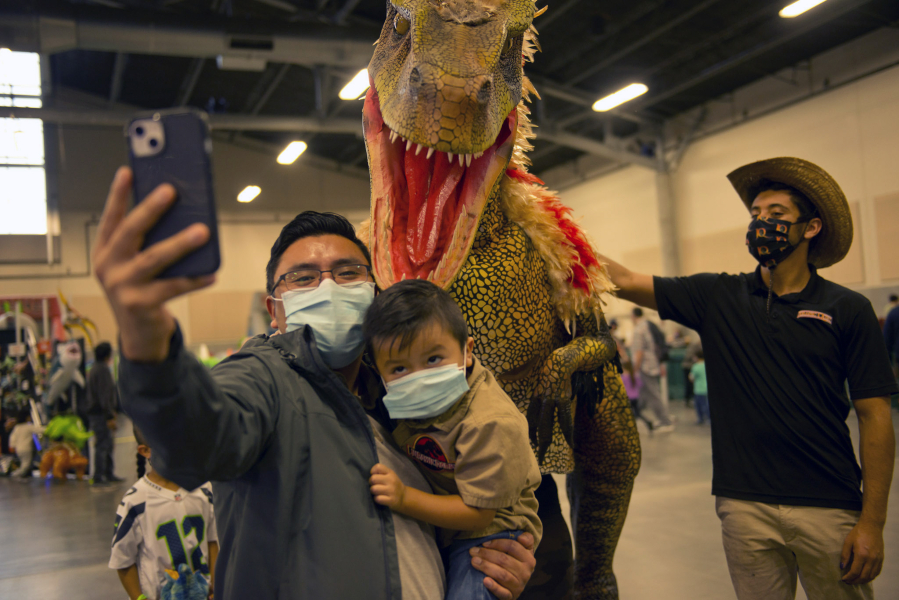 Julio Riscajche and his son Julian, 3, take a selfie on Saturday with Jojo the Deinonychus, with minder Brendon Grimes of Jurassic Quest at right. Families and dinosaur fans of all ages converged on the Clark County Event Center at the Fairgrounds to see a variety of life-size animatronic dinosaurs this weekend.