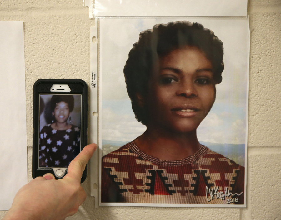 Brandon Johnson places his cellphone with a photo of a potential match up to an artist's drawing of Jane Seneca Doe which is taped to the wall of his office at the Grundy County coroner's office on Jan. 24, 2019, in Morris.