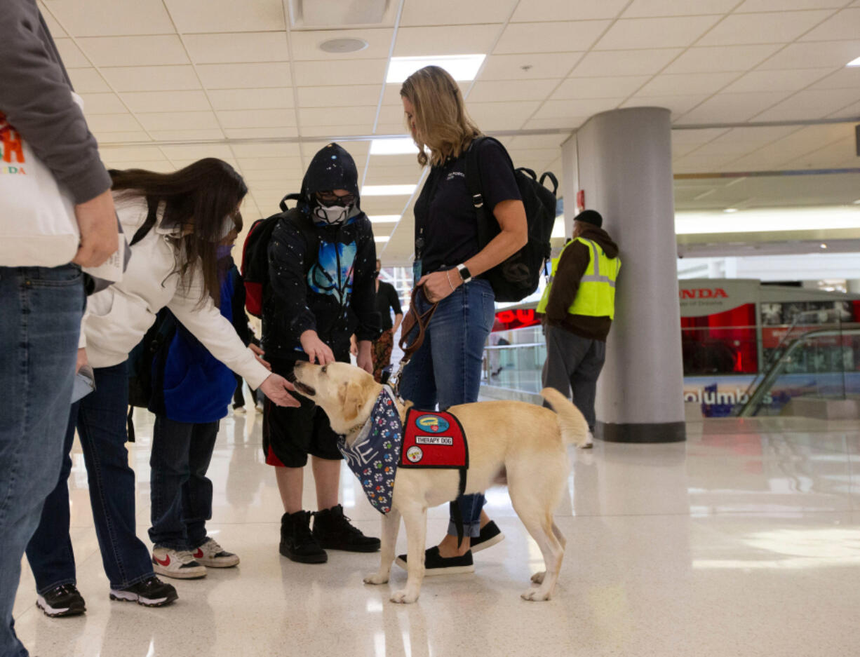 The Shoup family stops on the way to their flight to pet Yakeley, a dog from Paw Force One, at John Glenn Columbus International Airport in Columbus, Ohio.