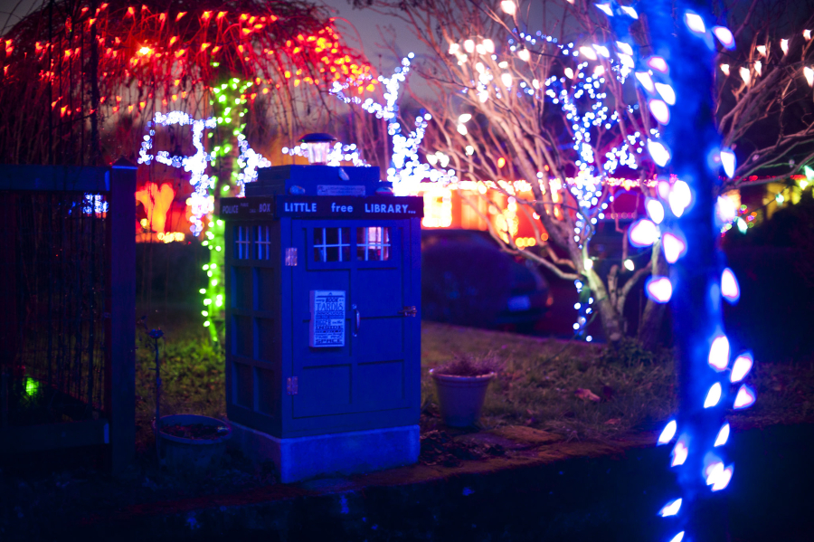 A Lincoln neighborhood house is illuminated with holiday lights while the TARDIS library stands sentinel in 2019.