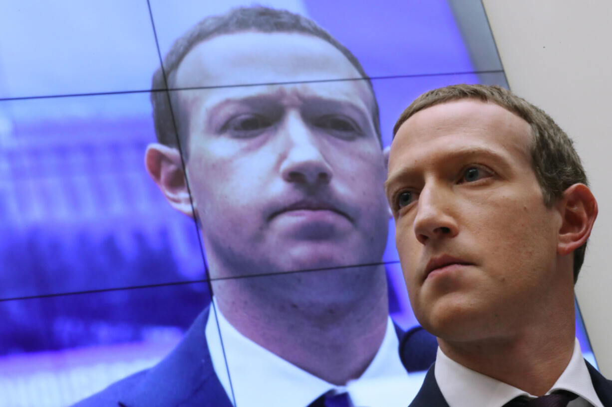 With an image of himself on a screen in the background, Facebook co-founder and CEO Mark Zuckerberg testifies before the House Financial Services Committee on Capitol Hill in 2019.