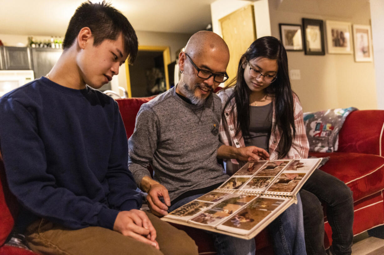 Son Duong, center, shows his children old photos of his family after he resettled to Washington. Duong, who was a refugee from Vietnam in the 1970s, had sponsors in the United States. His family is in the process of applying to be sponsors for an Afghan refugee family.