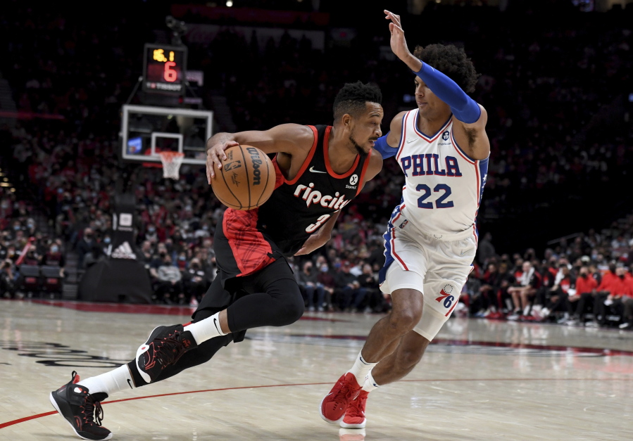 Portland Trail Blazers guard CJ McCollum, left, drives to the basket on Philadelphia 76ers guard Matisse Thybulle, right, during the second half of an NBA basketball game in Portland, Ore., Saturday, Nov. 20, 2021. The Trail Blazers won 118-111.