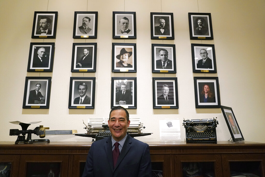 Steve Hobbs, who was sworn in as Washington Secretary of State, Monday, Nov. 22, 2021, at the Capitol in Olympia, Wash., poses in front of photos of the 15 people who previously held his office. Hobbs, a former state senator from Lake Stevens, Wash., is the first person of color to head the office and the first Democrat to serve as Secretary in more than 50 years. He replaces Republican Secretary of State Kim Wyman, who resigned to accept an election security job in the Biden administration. (AP Photo/Ted S.
