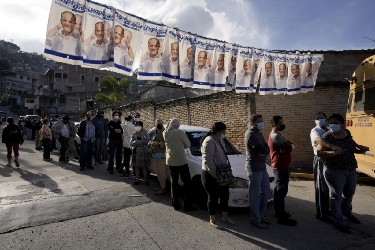 Voters line up outside a polling station during general elections in Tegucigalpa, Honduras, Sunday, Nov. 28, 2021.