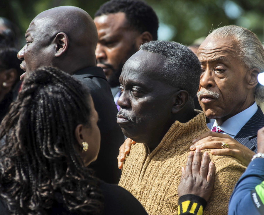 Rev. Al Sharpton, right, and Barbara Arnwine, founder of the Transformative Justice Coalition, rest their hands on Marcus Arbery's shoulder as Benjamin Crump, left, one of the Arbery family's lawyers, speaks about the slain Ahmaud Arbery outside the Glynn County courthouse, Wednesday, Nov. 10, 2021, in Brunswick, Ga. Rev. Sharpton led a prayer and spoke out against injustice during the noon break in the trial of three men charged with murder in Ahmaud Abery's shooting death.