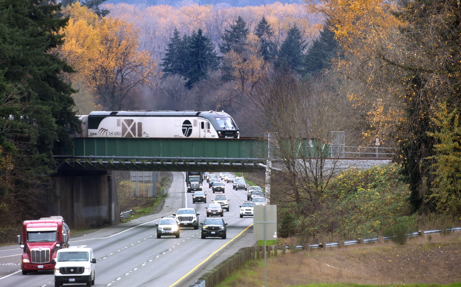 The northbound Amtrak Cascades train rolls across the Interstate 5 overpass in DuPont, Wash., on Thursday, Nov. 18, 2021.