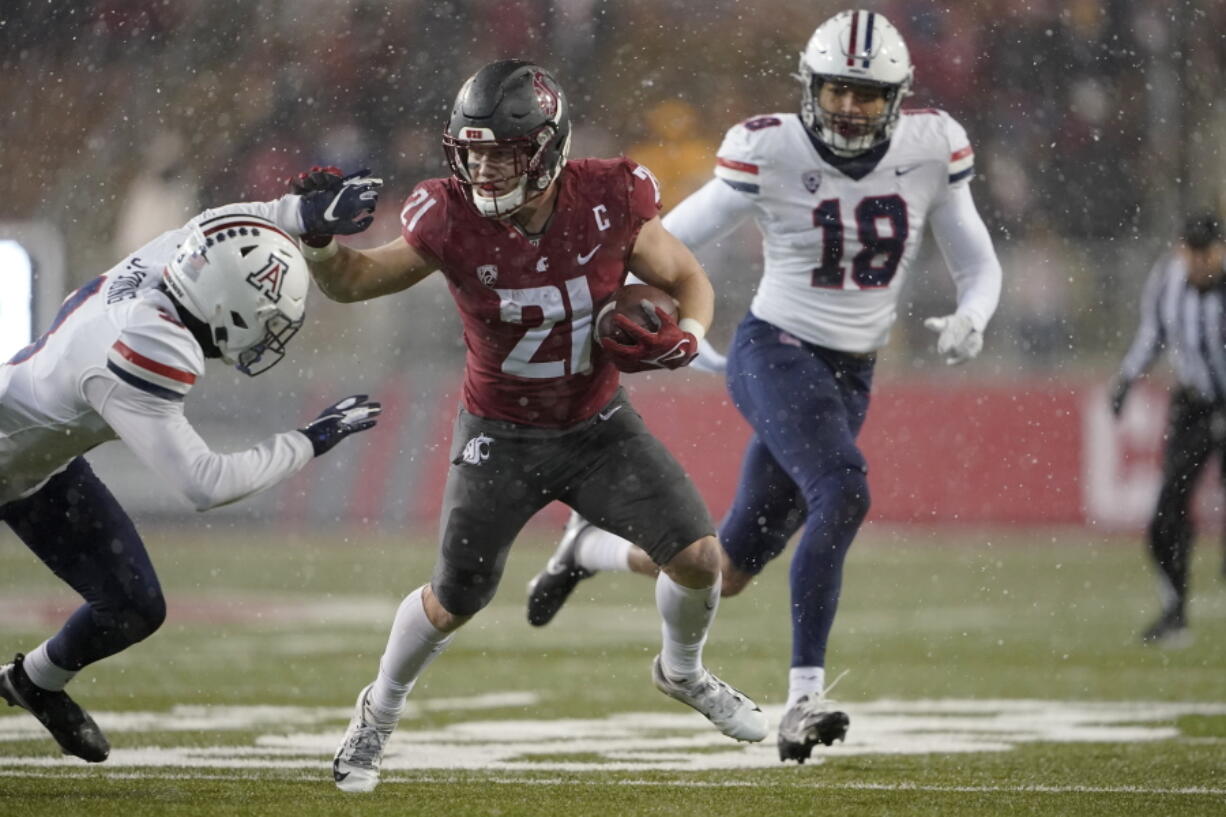 Washington State running back Max Borghi (21) fends off a tackle from Arizona free safety Jaydin Young, left, as he runs for a touchdown and Arizona linebacker Kenny Hebert (18) closes in during the first half of an NCAA college football game, Friday, Nov. 19, 2021, in Pullman, Wash. (AP Photo/Ted S.