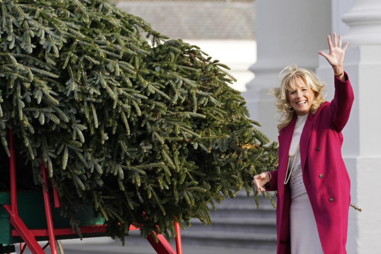 First lady Jill Biden waves to people watching as she looks over the official White House Christmas Tree, grown in North Carolina, as it arrives at the White House in Washington, Monday, Nov. 22, 2021.